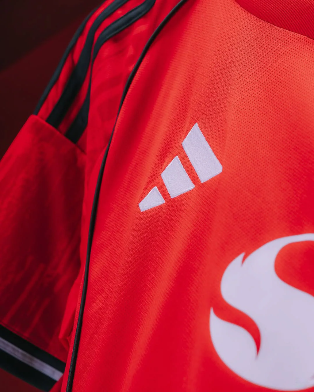 Close-up of Hoop Store Manchester United 2025-26 home jersey showing Adidas logo and red fabric details