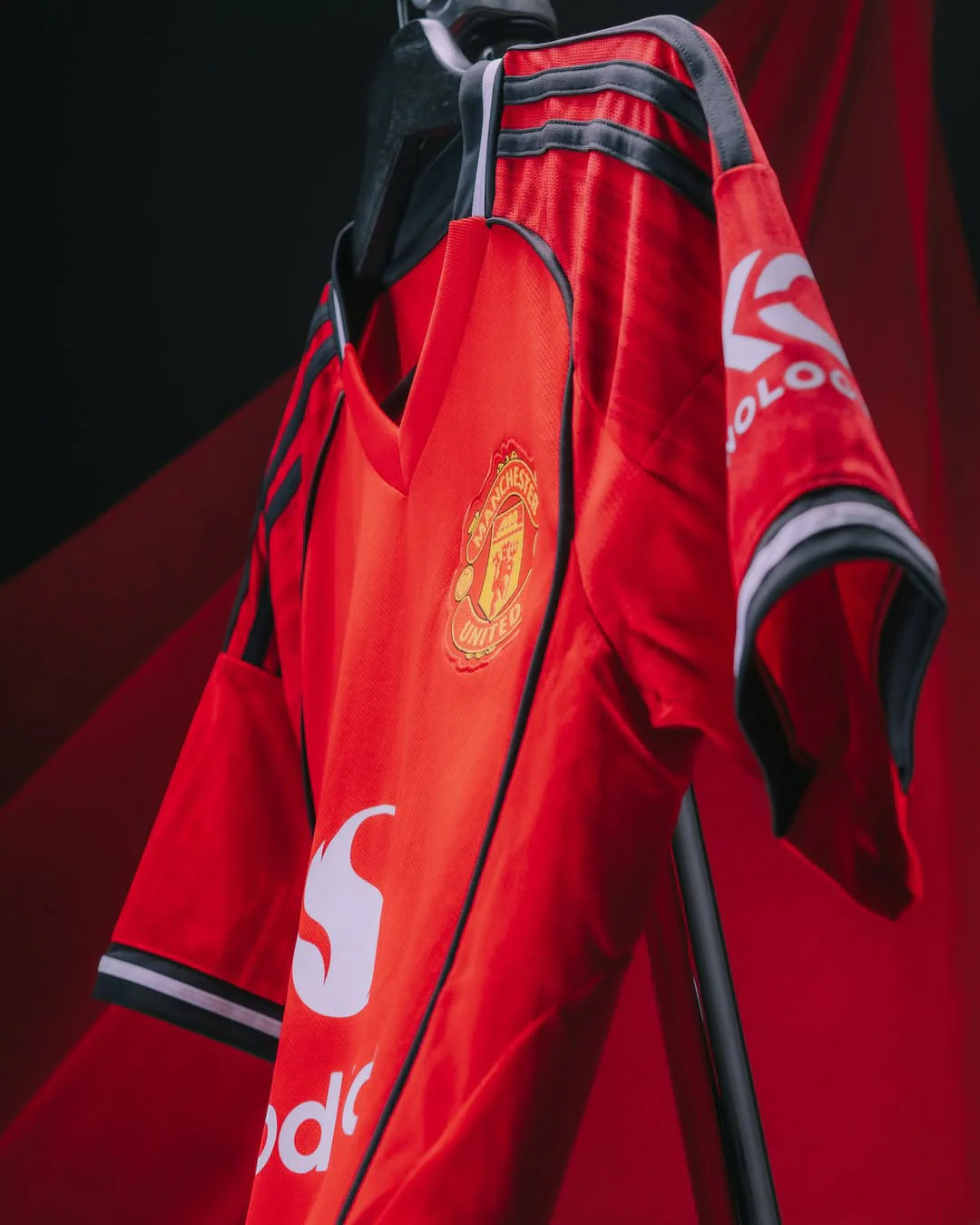 Hoop Store Manchester United 2025-26 home jersey in red with black and white detailing hanging on a rack