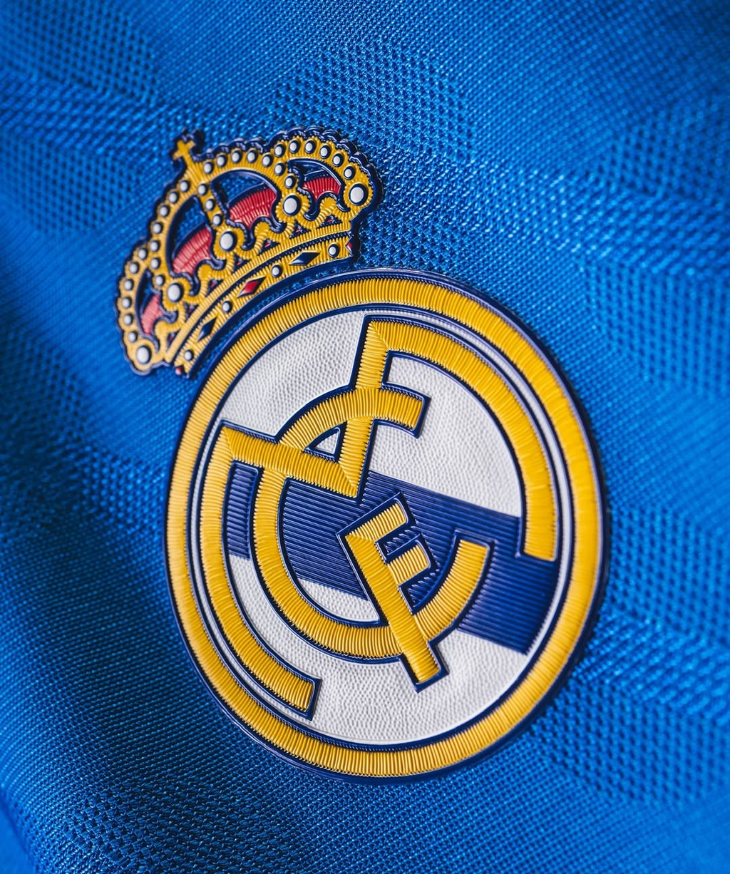 Close up embroidered Real Madrid crest on blue textured fabric Hoop Store Real Madrid Third Jersey 2025-26