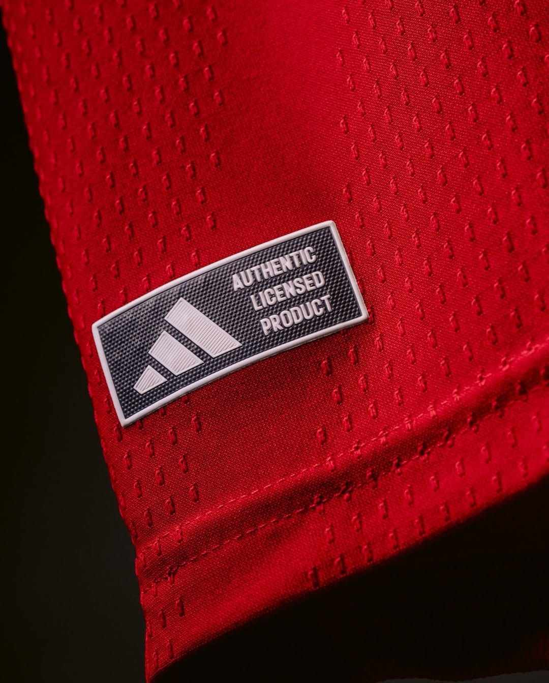 Close-up of the Adidas label on Manchester United Home Jersey 2026-27 in vibrant red fabric