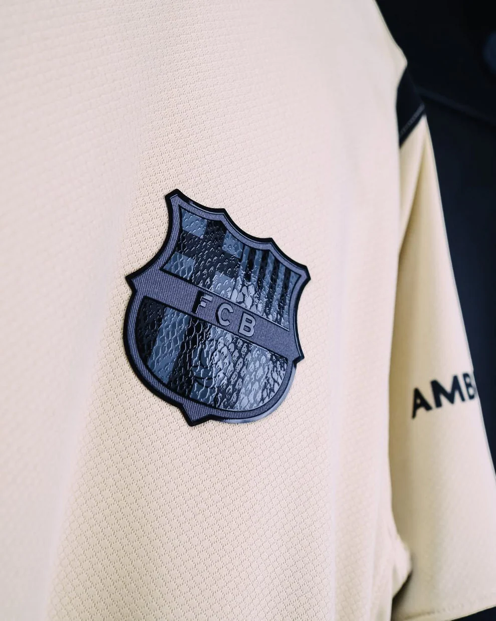 Hoop Store Barcelona away jersey 2025-26 cream close up with black embossed FCB crest and textured fabric