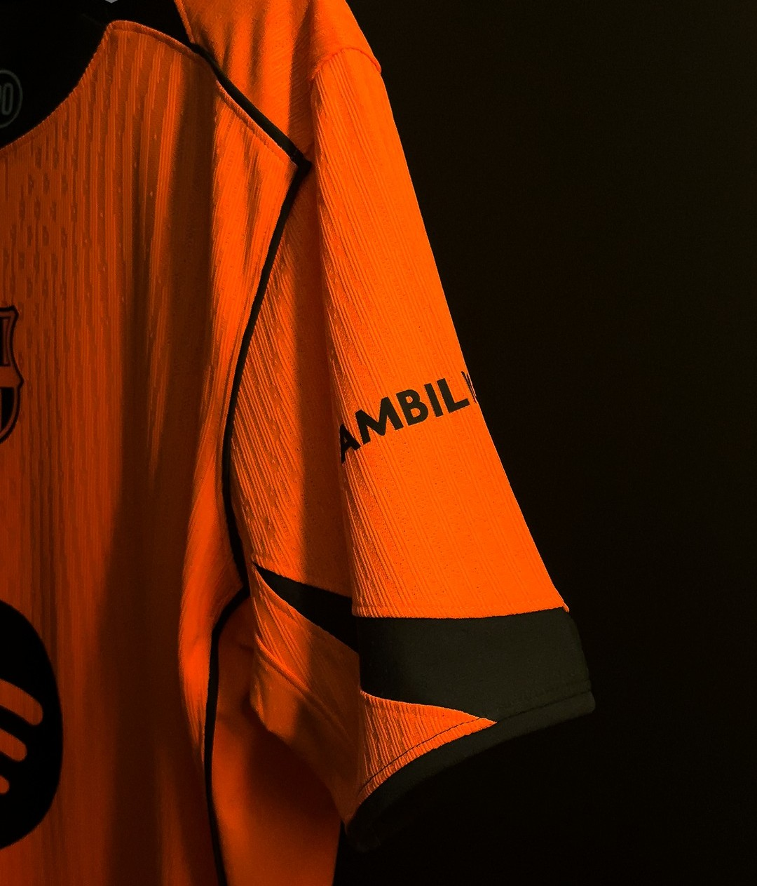 Hoop Store close up of orange Barcelona third jersey 2025-26 player version showing sleeve black piping and crest