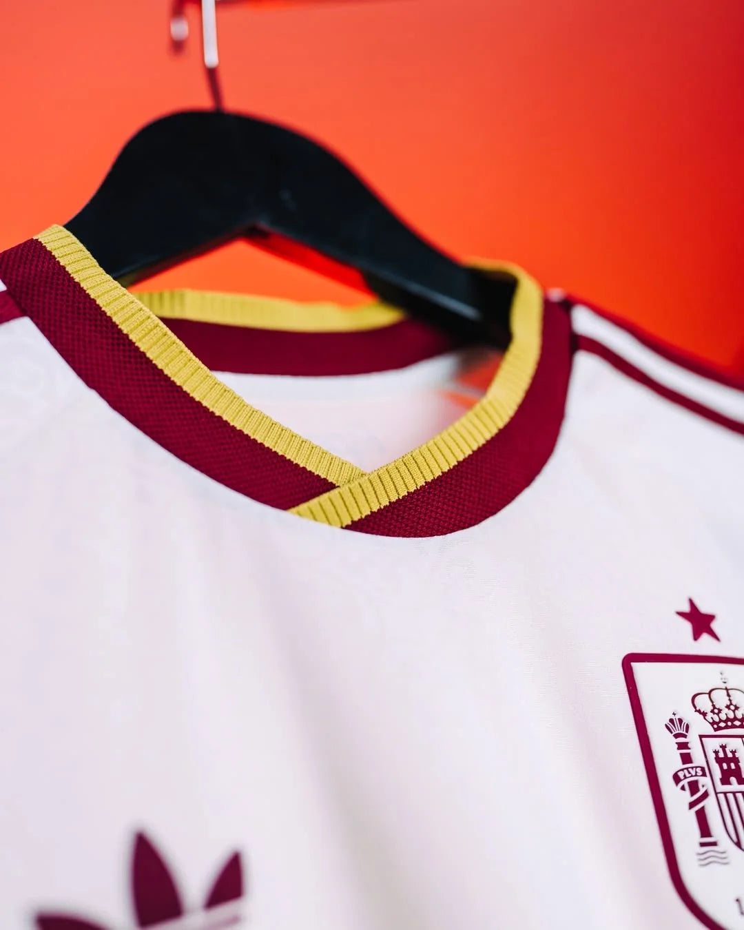 Spain Away Lamine Yamal FIFA WC Jersey 2026 with maroon and yellow collar design hanging on display